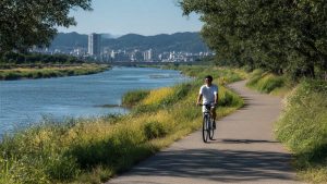 川沿いサイクリングロードをクロスバイクで快適に走る日本人サイクリストのアイキャッチ画像