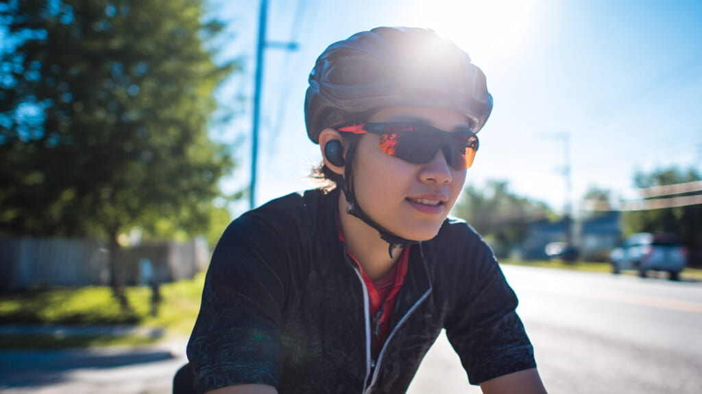 骨伝導イヤホンを装着して走行する日本人サイクリスト