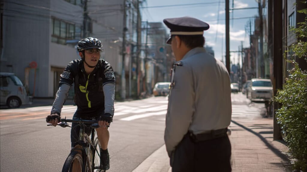 日本の道路で警察官と自転車利用者が交通ルールについて確認している場面