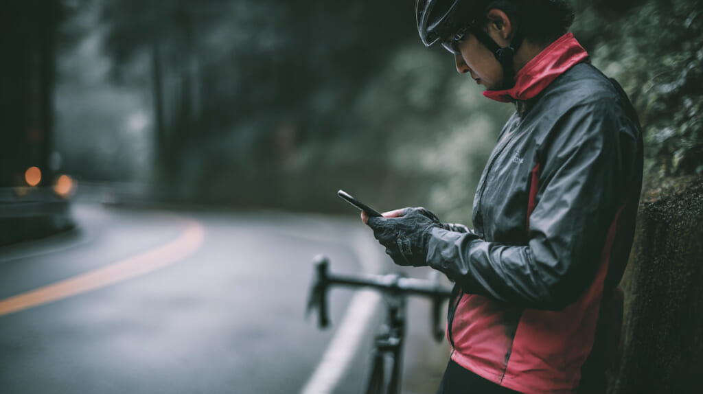 自転車を止めてスマートフォンを確認する日本人利用者