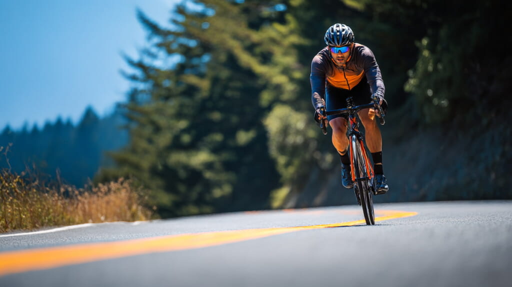 前傾姿勢でスピード走行する日本人男性サイクリスト