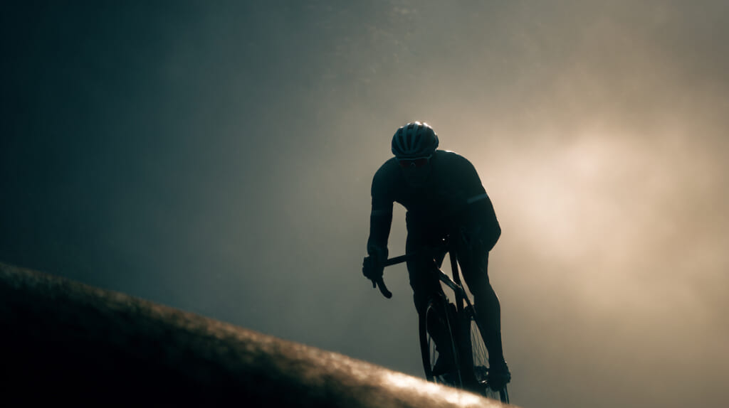 坂道を前にしてギアを軽くする準備をする日本人サイクリストのイメージ