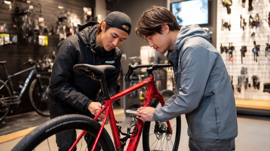 整備済みクロスバイクを受け取る日本人客と自転車店スタッフ