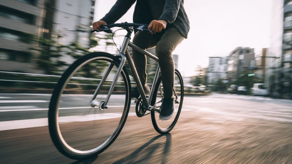 　スーツ姿の日本人男性がクラシックなクロスバイクで通勤する街中の風景