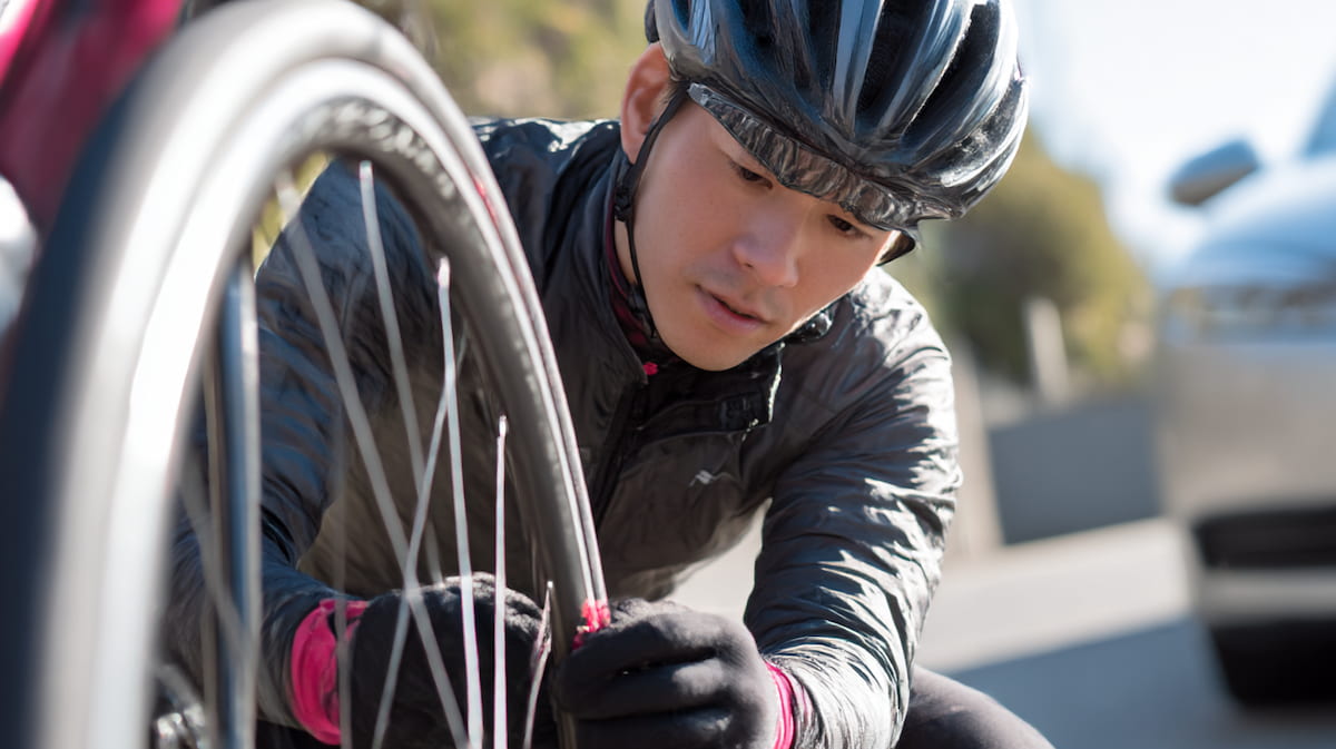 クロスバイクのタイヤを点検する日本人男性の様子
