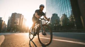 夕暮れの都市を軽量カーボンクロスバイクで走る日本人男性ライダーの躍動感あるシーン