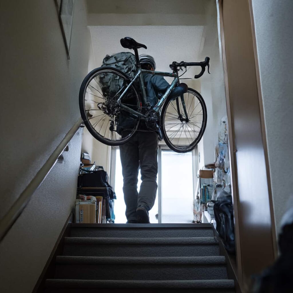 軽量クロスバイクを片手で持ち上げる日本人女性のイメージ